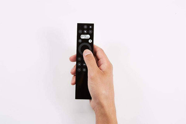 A hand holding the Caavo remote