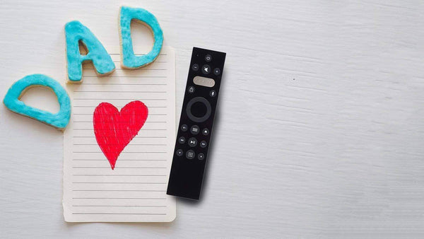 Display of the Caavo remote next to a piece of paper with a red heart on it and the word "Dad" spelled out in cookies
