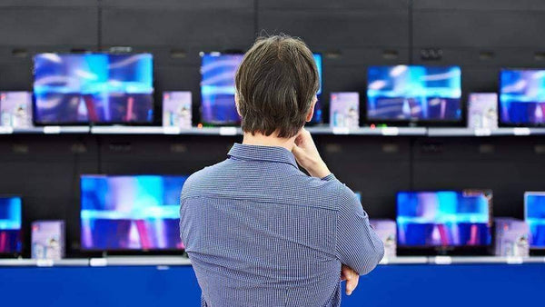 A customer is at an electronic store pondering what kind of TV he should buy